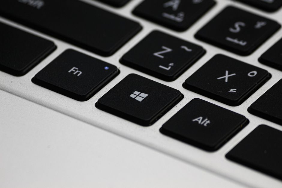 A clean, professional desk setup with a person's hands on a laptop next to a set of house keys, illustrating the efficiency of online real estate transactions.