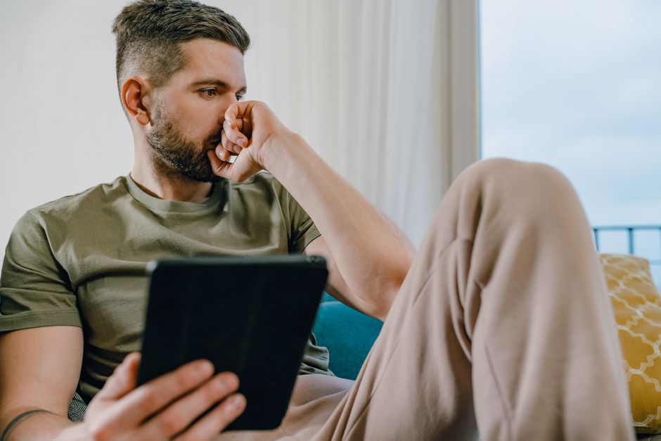 Real estate agent or home buyer stands in a bright, modern living room, using a tablet to analyze property data, symbolizi...