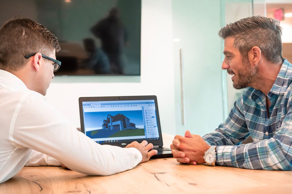 Two professionals in a bright, modern office collaborate over a laptop and documents, demonstrating the expertise and client-focused strategy of a leading real estate firm.