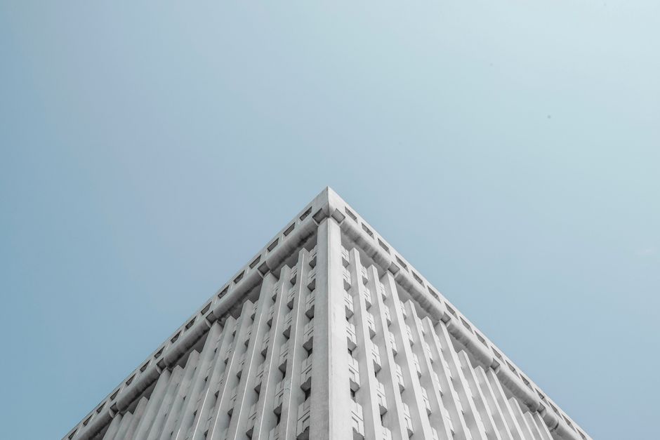 An upward-looking shot of a modern skyscraper with clean architectural lines against a clear blue sky, symbolizing a strong and authoritative real estate firm.